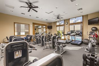 A gym with a variety of equipment including treadmills, weights, and exercise machines.